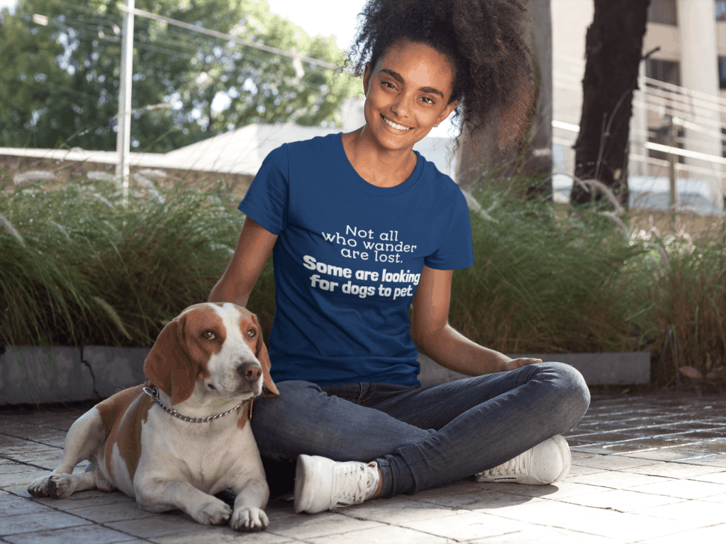 girl petting a beagle dog wearing a tshirt that says All who wander are not Lost. Some are looking for dogs to pet.